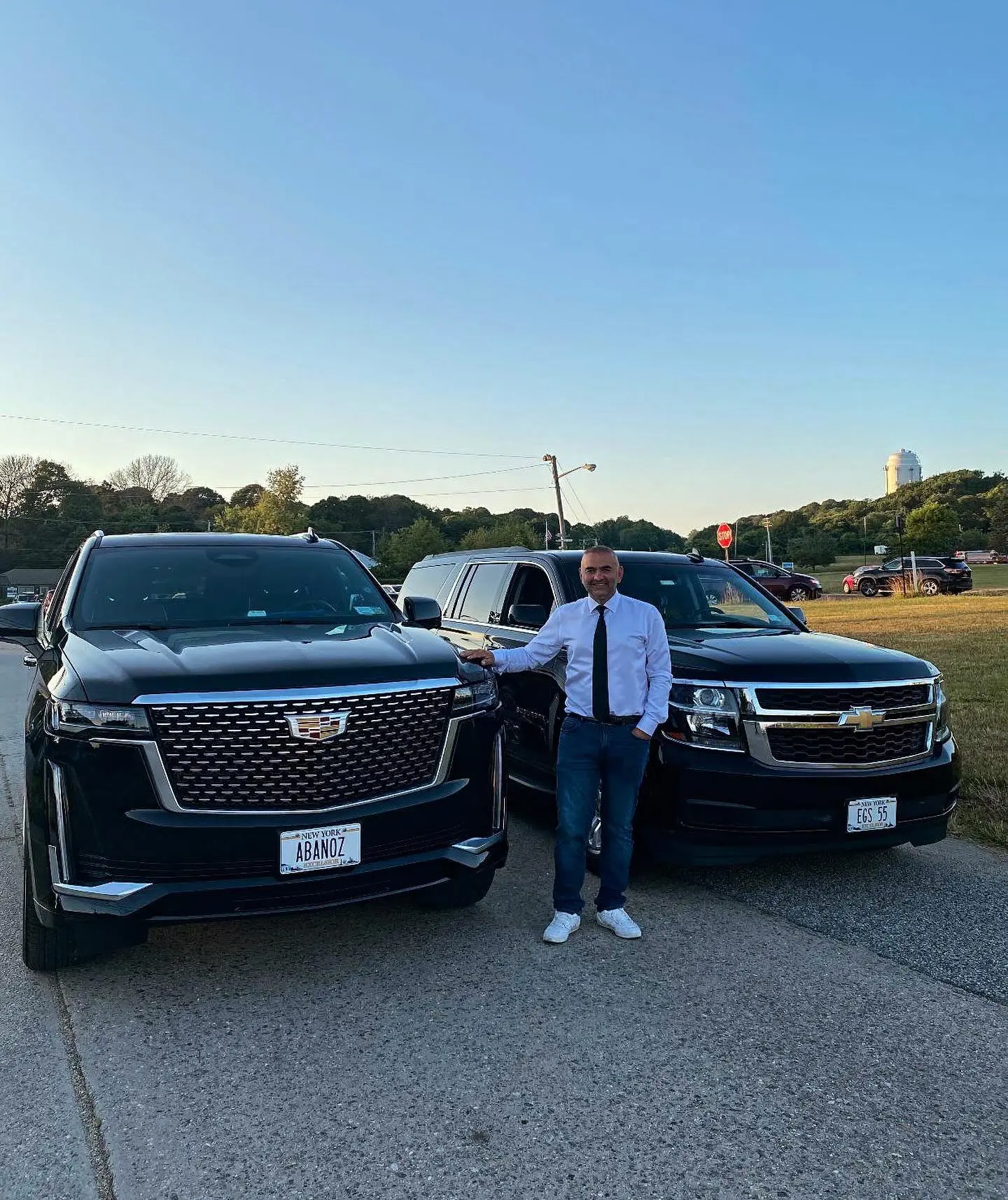Man standing between two black SUVs.