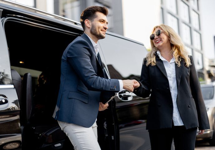 Man and woman shaking hands by car.