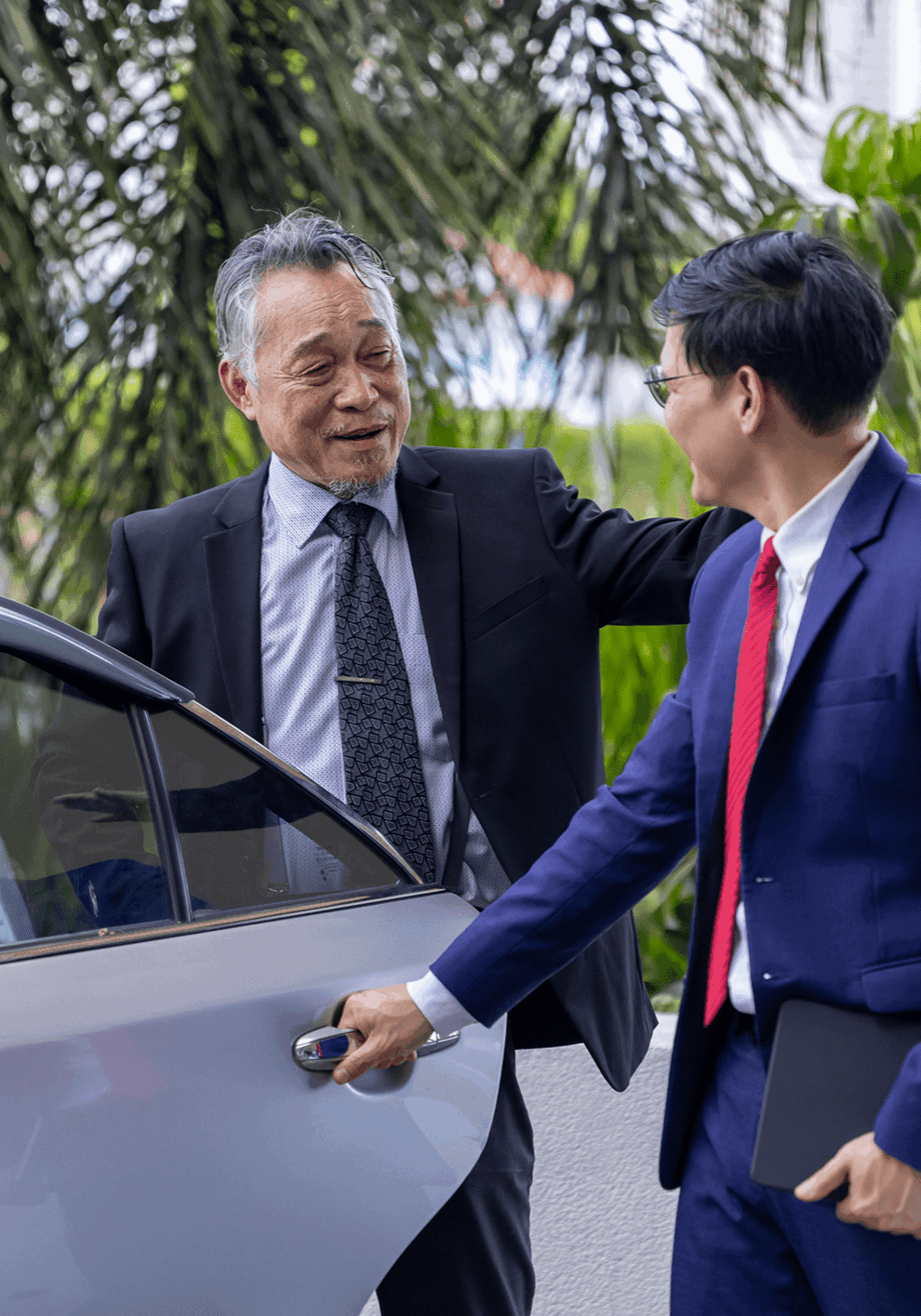 Two businessmen greeting by a car.