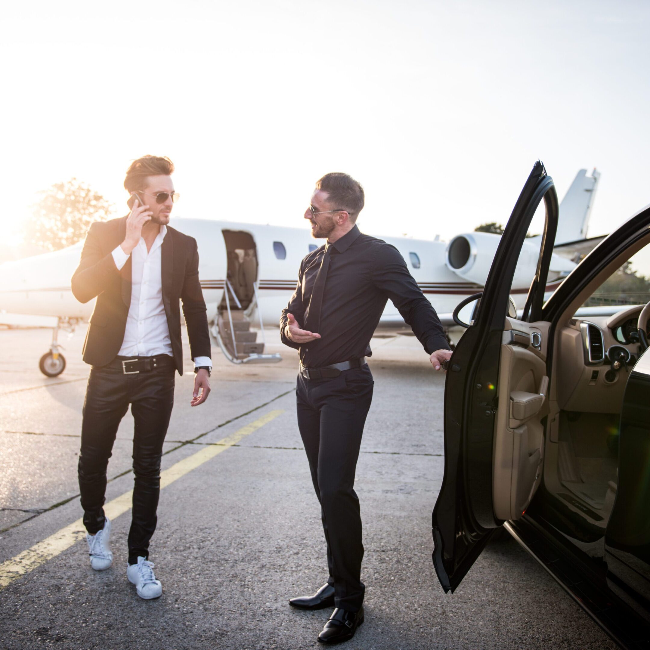 Two men talking near private jet.